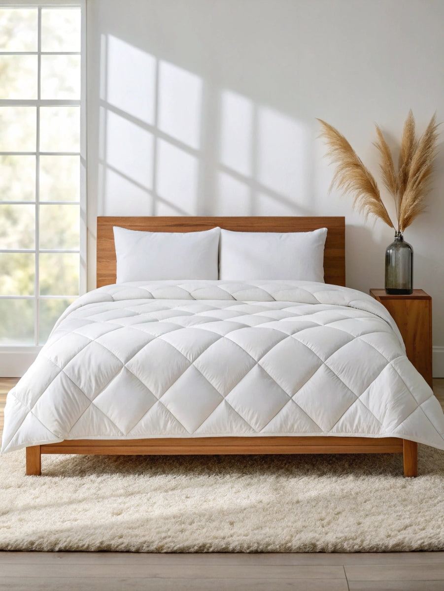 Minimalist bedroom with white bamboo quilted comforter on a wood bed, pampas decor, and natural light from large windows.
