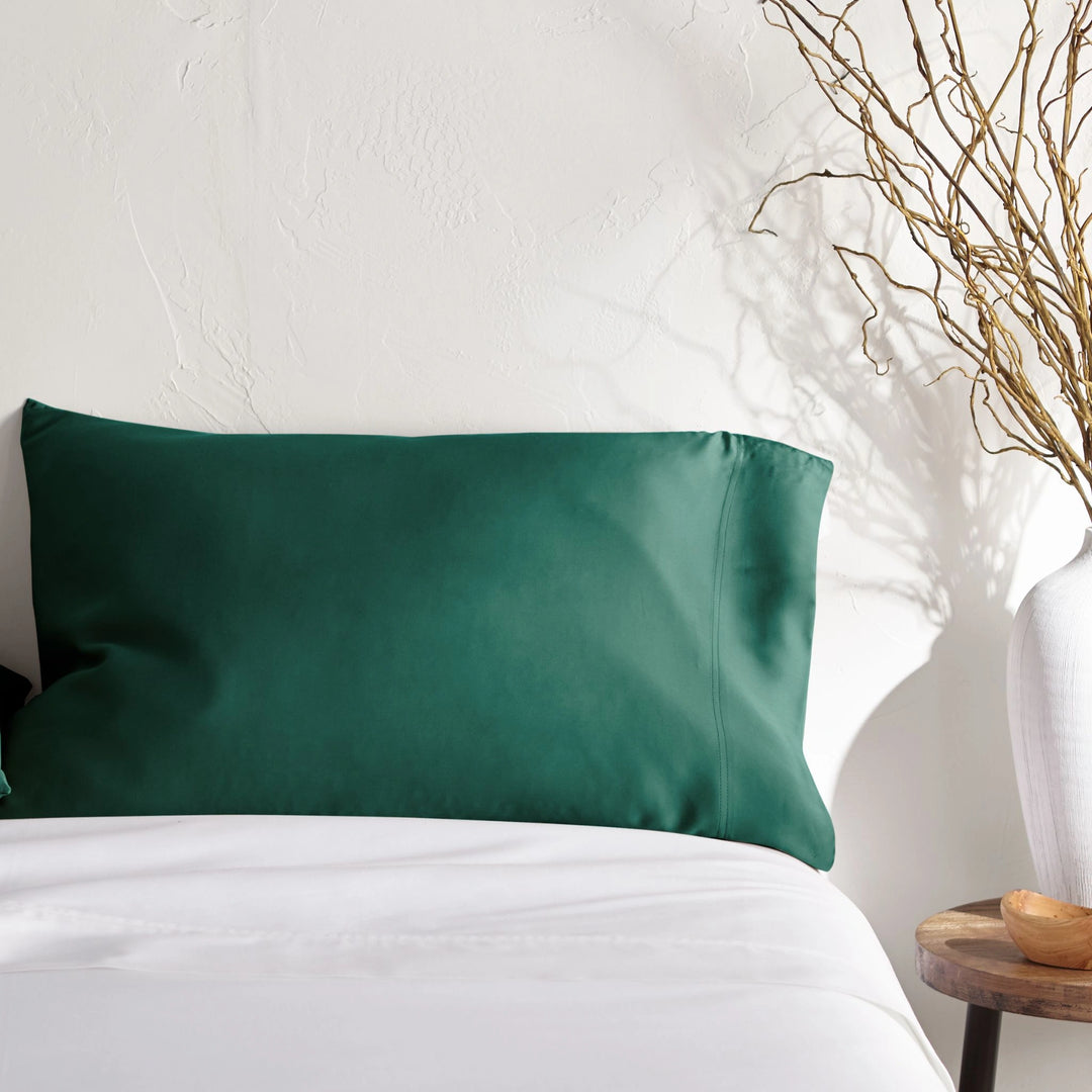 emerald green bamboo pillowcase on a emerald green bed from the Signature Collection, styled with vase decor and natural light