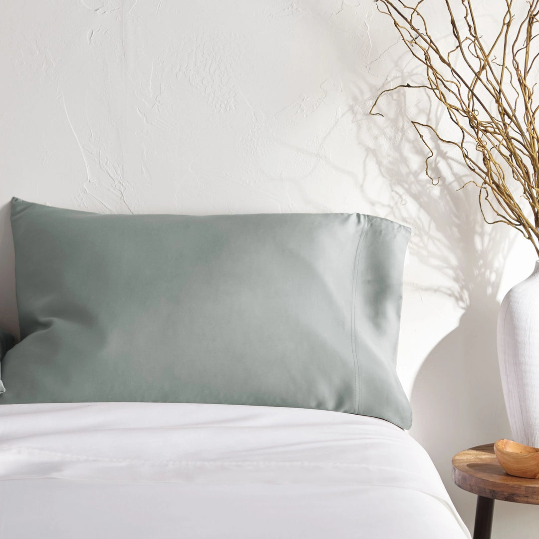 silver bamboo pillowcase on a white bed from the Signature Collection, styled with vase decor and natural light