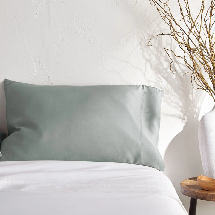 silver bamboo pillowcase on a white bed from the Signature Collection, styled with vase decor and natural light
