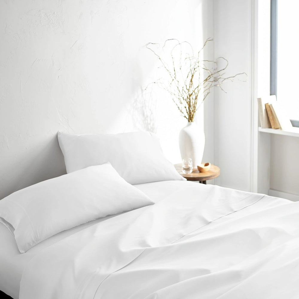 white bamboo bed sheets with sateen weave from the Signature Collection, three-quarter angle showing natural folds and soft lighting from nearby window