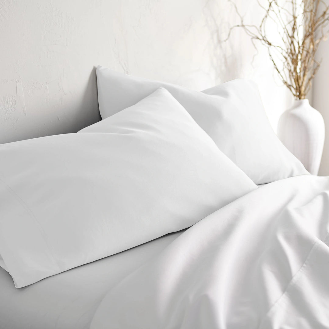 white bamboo pillowcases from the Signature Collection, styled on white bedding at an angle with soft natural light