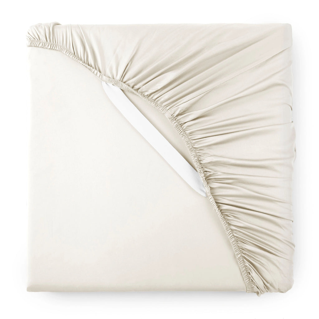 Cream bamboo sateen fitted sheet corner with white elastic strap, showing snug fit and smooth fabric texture