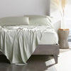 Sage bamboo bed sheets with sateen weave from the Premium Collection, shown front view with matching pillowcases and a modern nightstand