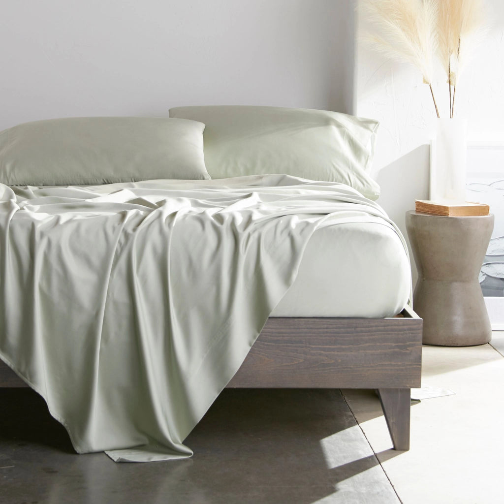 Sage bamboo bed sheets with sateen weave from the Premium Collection, shown front view with matching pillowcases and a modern nightstand