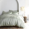 Sage bamboo sateen bedding set with pillowcases and duvet on king bed, styled in minimal bedroom with rustic wood floors and ceramic vase decor