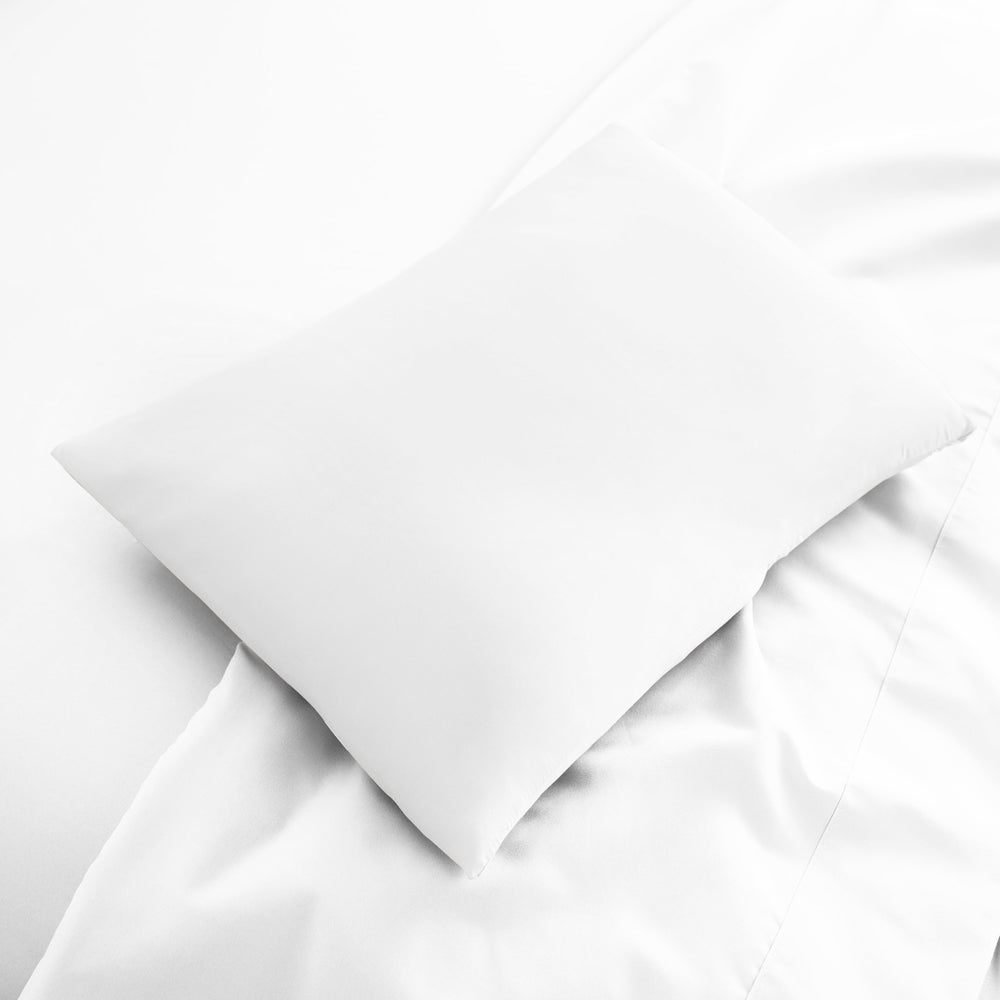 White bamboo viscose sateen lumbar pillowcase from the Signature Collection, displayed flat on white bedding