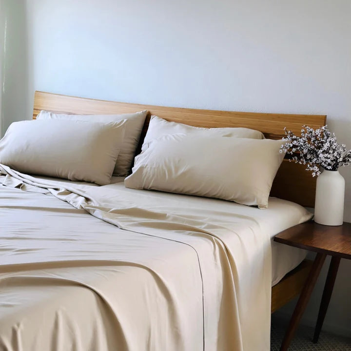 Summer Sand bamboo copper-infused bed sheet set on a neatly made bed with a wooden headboard, featuring breathable, hypoallergenic, and cooling sheets and pillowcases, styled with a bedside table and decorative flowers.