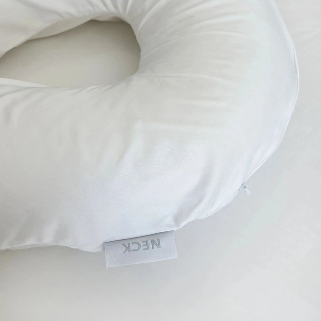 Close-up of white bamboo neck pillowcase featuring a visible brand tag, highlighting soft, breathable fabric and eco-conscious design