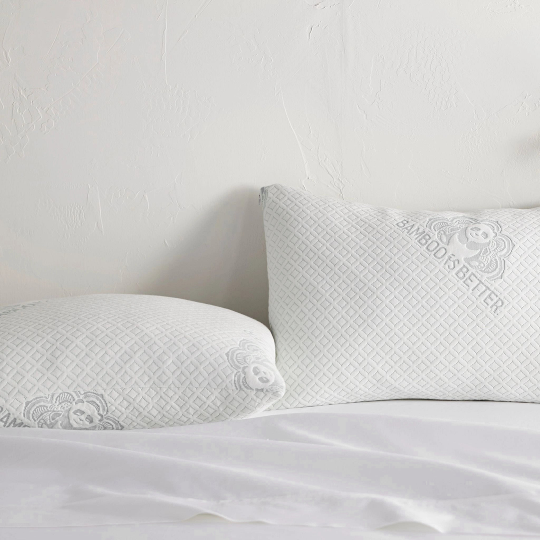 Pair of adjustable cooling bamboo pillows on a neatly made white bed.