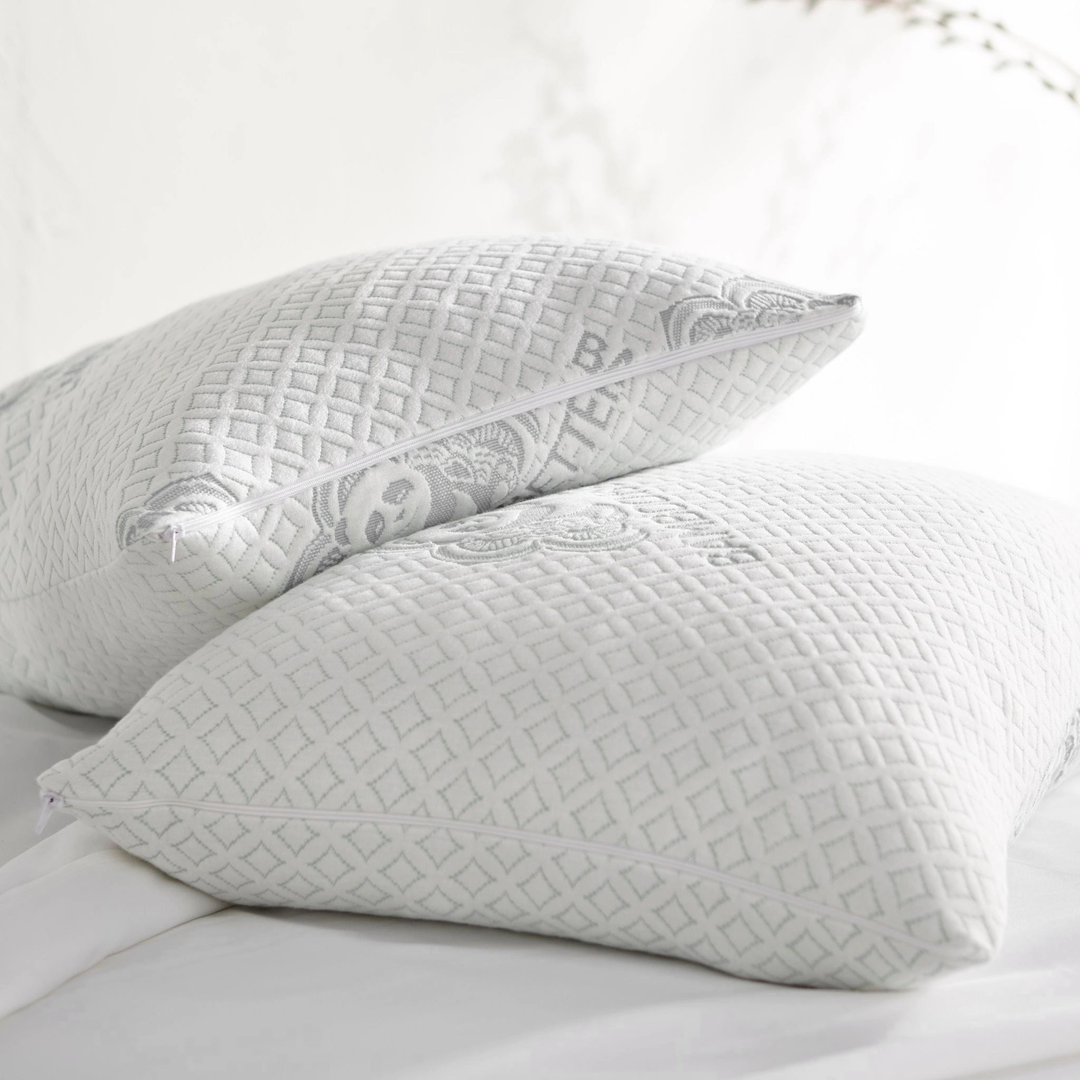 Two adjustable bamboo cooling pillows with zippered covers on a white bed – breathable, washable, and eco-friendly design for hot sleepers.