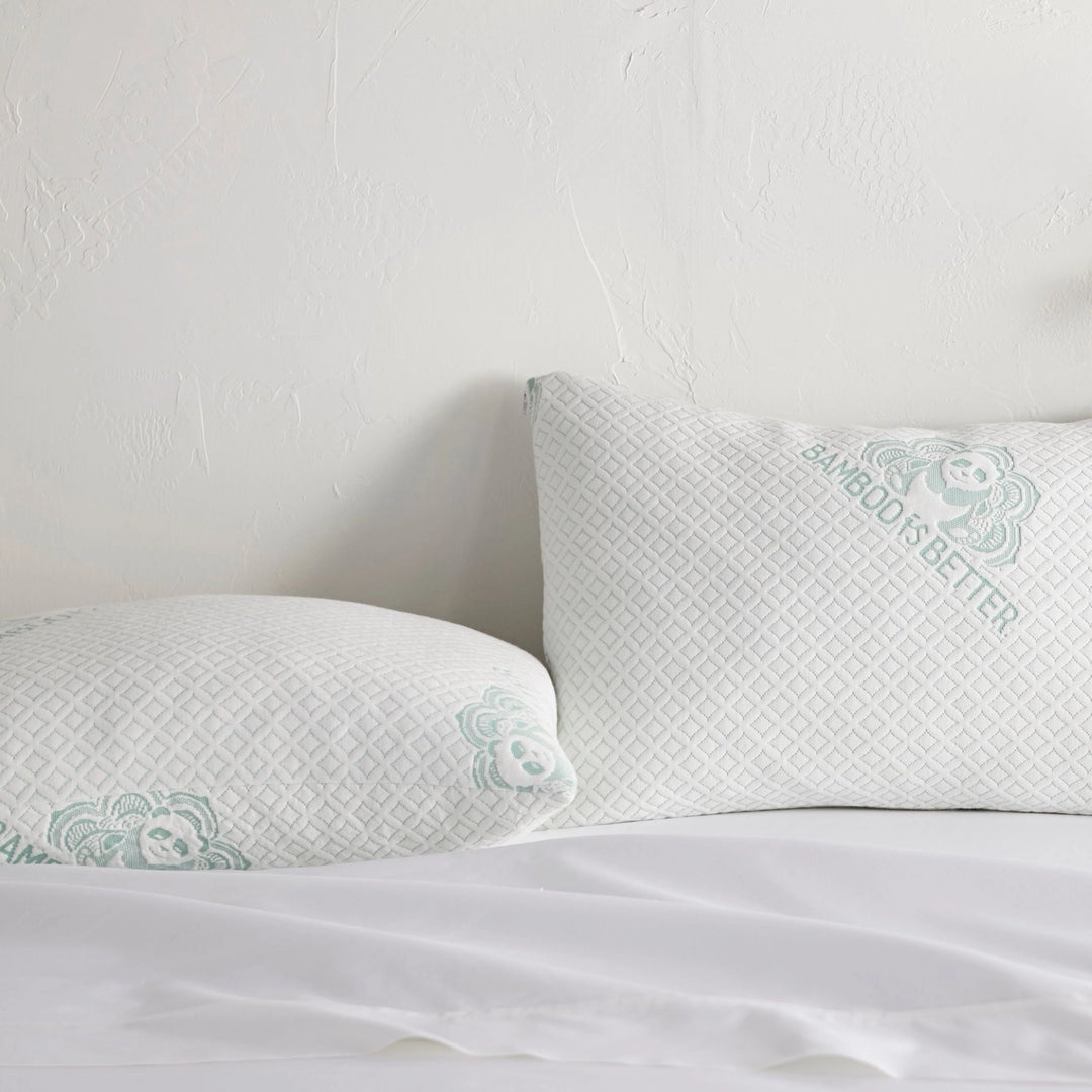 Pair of adjustable cooling bamboo pillows on a neatly made white bed.