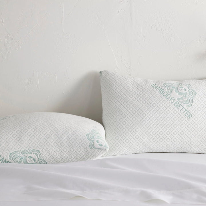 Pair of adjustable cooling bamboo pillows on a neatly made white bed.