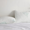 Pair of adjustable cooling bamboo pillows on a neatly made white bed.