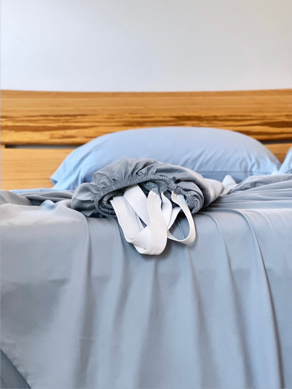 Dusty Blue copper-infused bamboo fitted sheet — corner detail showing the elastic hem and reinforced corner straps for a secure fit.