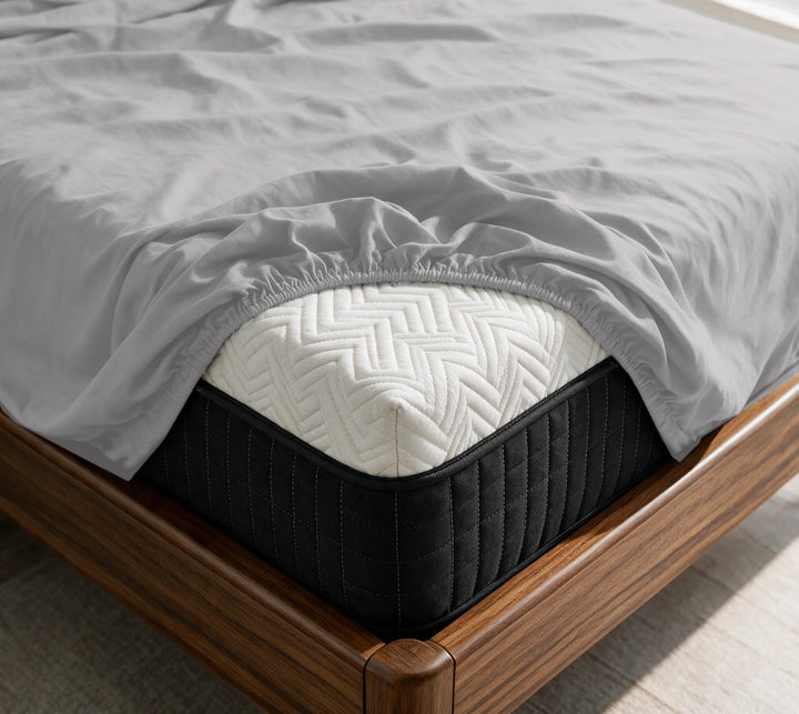 Feather Gray copper-infused bamboo fitted sheet on a mattress in a sunlit walnut bedroom — breathable, cooling sateen weave.