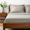 Side angle shot from pillow-end showing feather gray  bamboo pillowcases and sheet set with decorative plant and soft lighting.