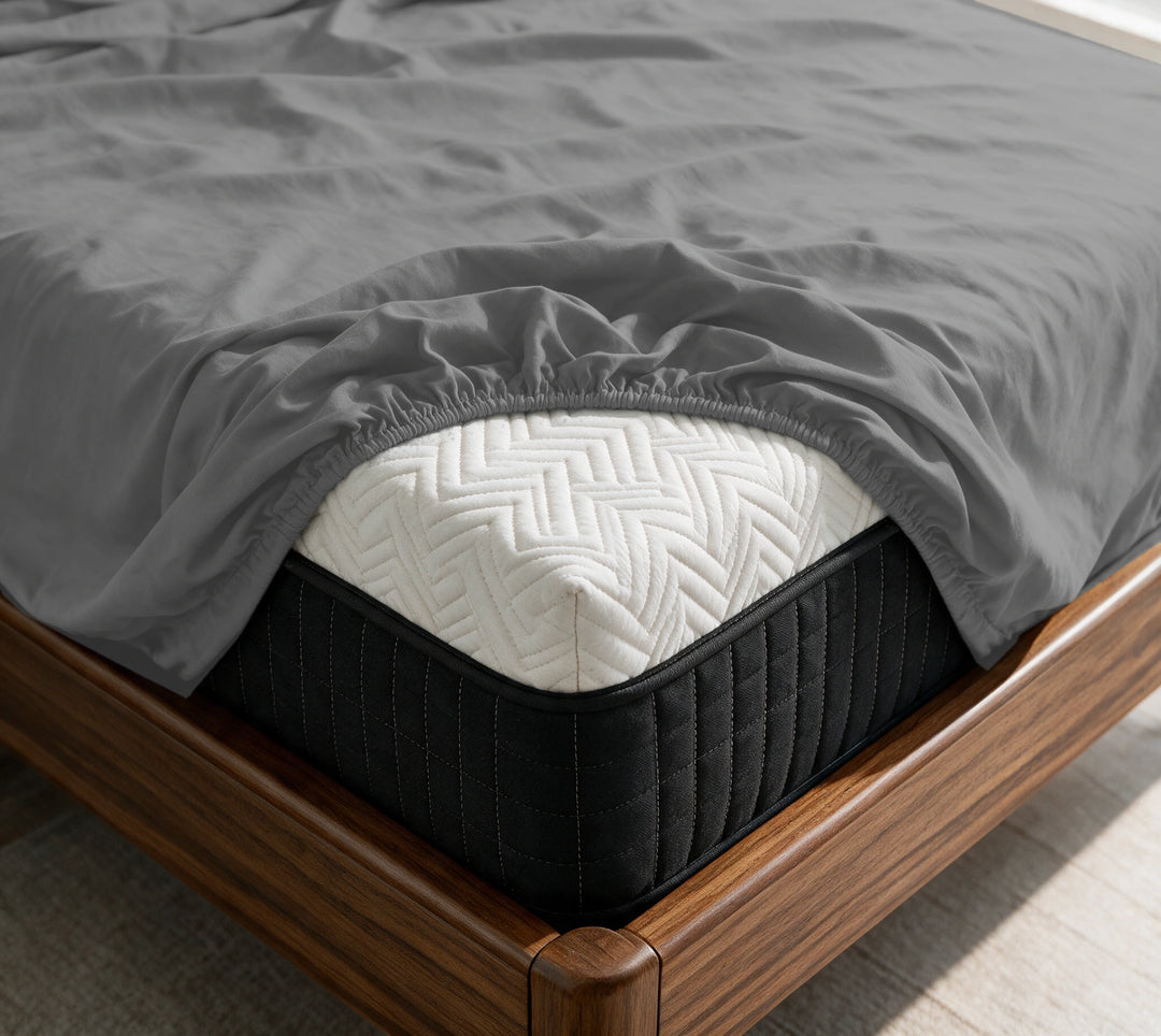 Graphite Gray copper-infused bamboo fitted sheet on a mattress in a sunlit walnut bedroom — breathable, cooling sateen weave.