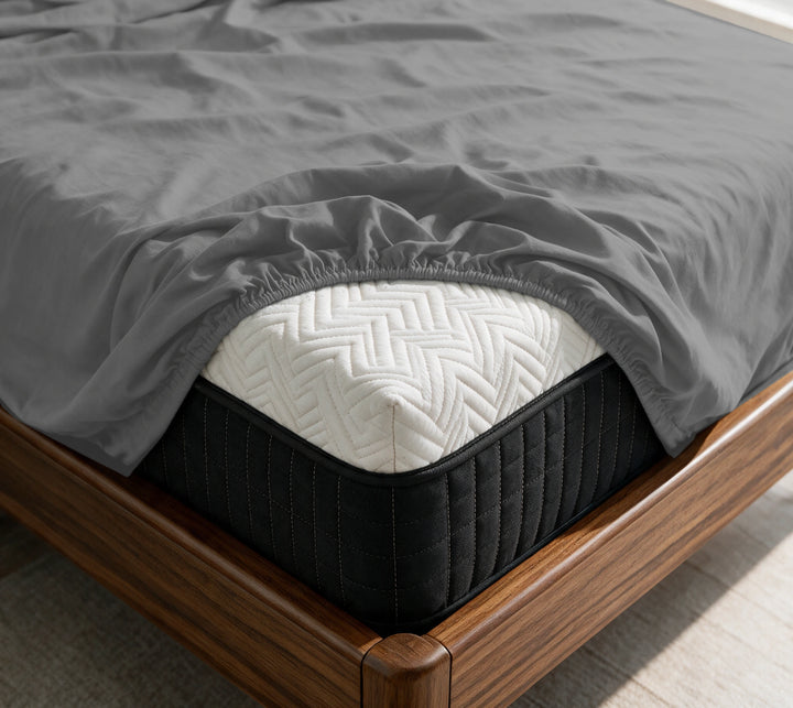 Graphite Gray copper-infused bamboo fitted sheet on a mattress in a sunlit walnut bedroom — breathable, cooling sateen weave.