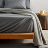 feather gray  bamboo sheets in a cozy lifestyle setting with a soft throw blanket, open book, and coffee cup, highlighting texture and drape