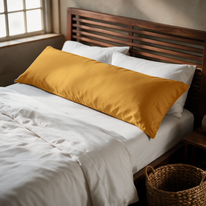 Mustard copper-infused bamboo viscose body pillowcase on a walnut bed, alternate three-quarter angle from the foot of the bed.