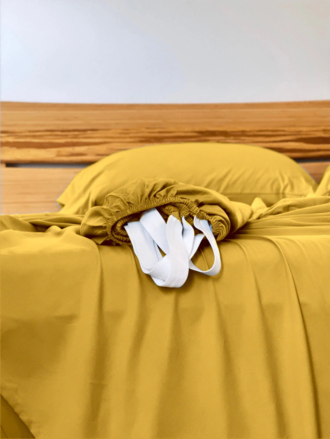 Mustard copper-infused bamboo fitted sheet — corner detail showing the elastic hem and reinforced corner straps for a secure fit.