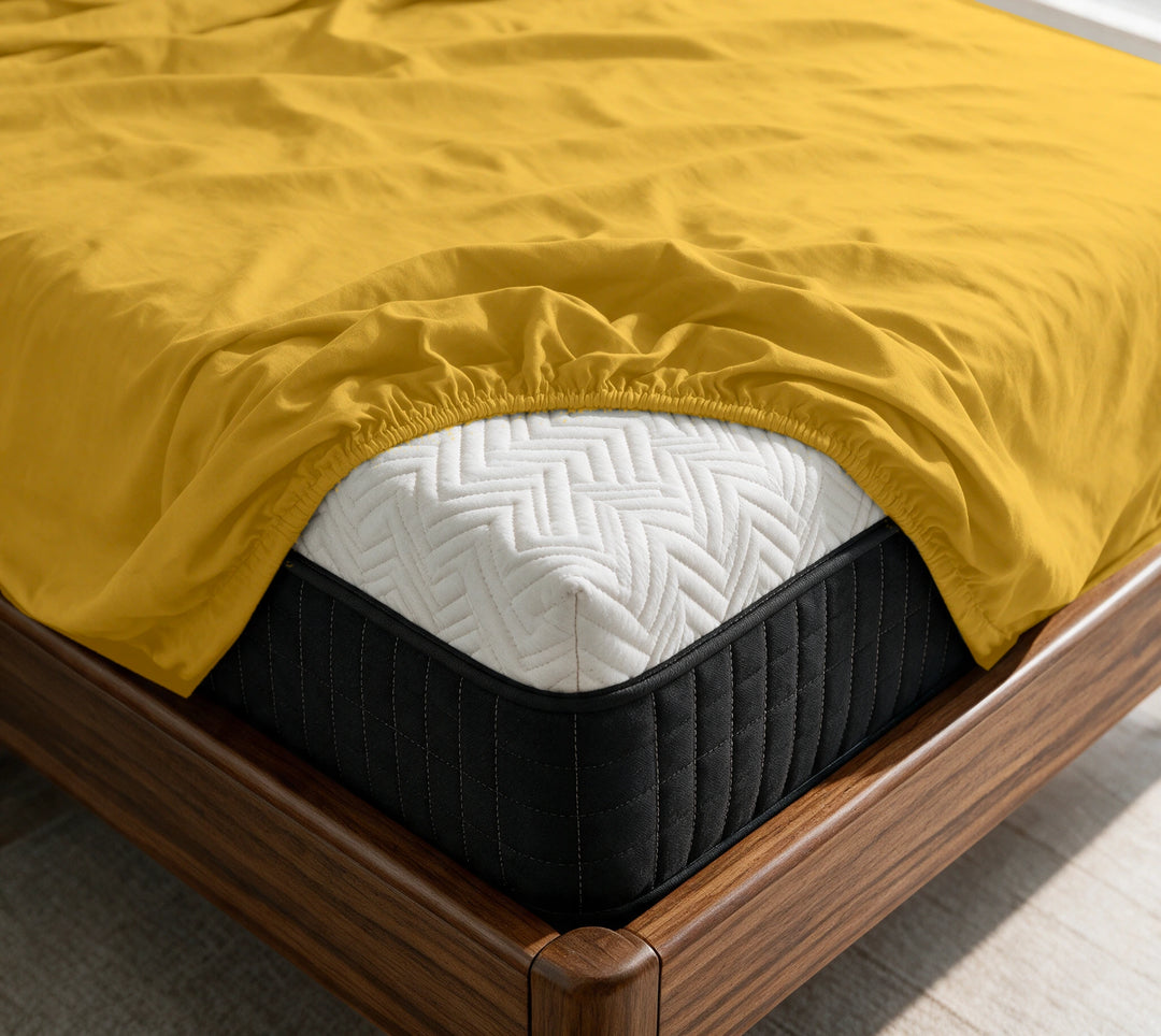 Mustard copper-infused bamboo fitted sheet on a mattress in a sunlit walnut bedroom — breathable, cooling sateen weave.