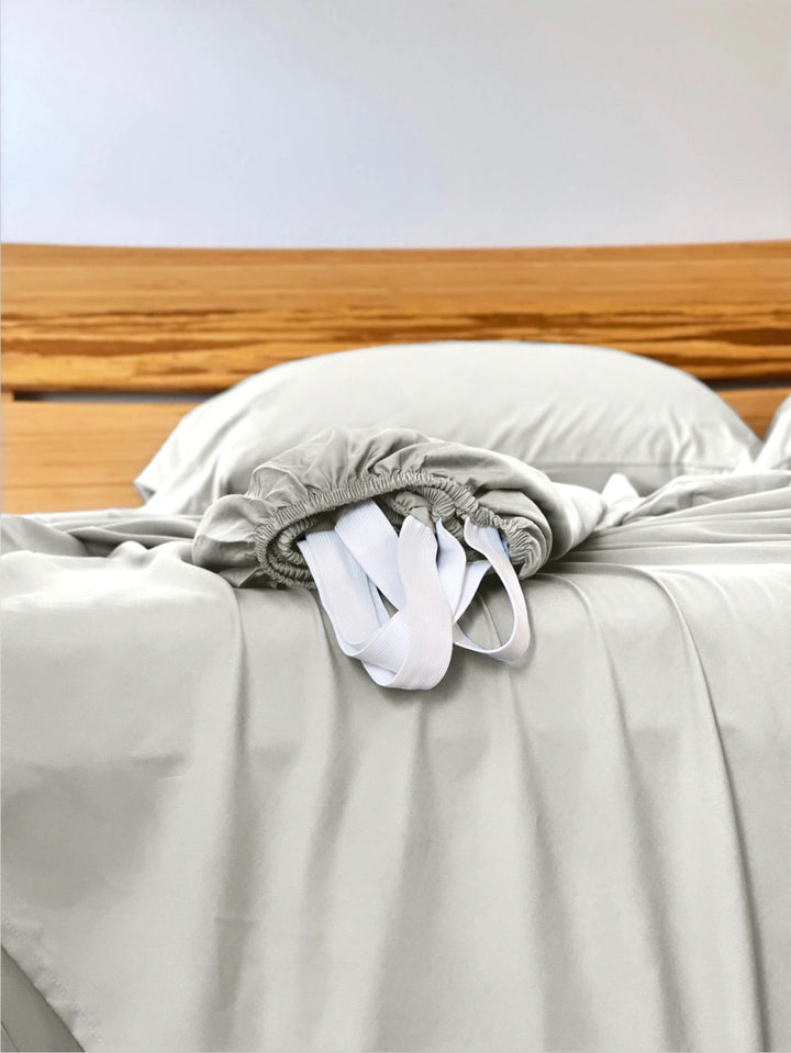 Powder White copper-infused bamboo fitted sheet — corner detail showing the elastic hem and reinforced corner straps for a secure fit.