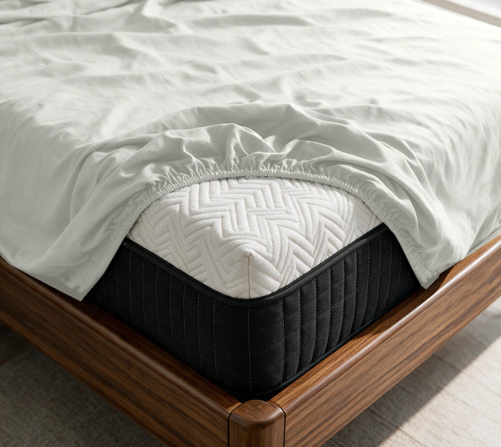 Powder White copper-infused bamboo fitted sheet on a mattress in a sunlit walnut bedroom — breathable, cooling sateen weave.