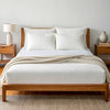 Angled view from the foot of the bed showing the powder white bamboo sheets with a soft finish and elegant bed styling.