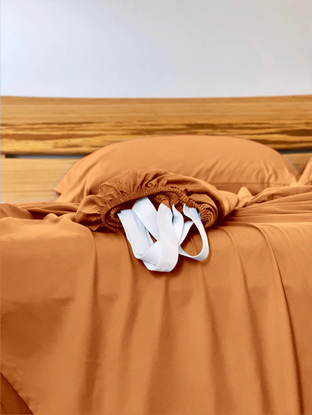 Rust copper-infused bamboo fitted sheet — corner detail showing the elastic hem and reinforced corner straps for a secure fit.