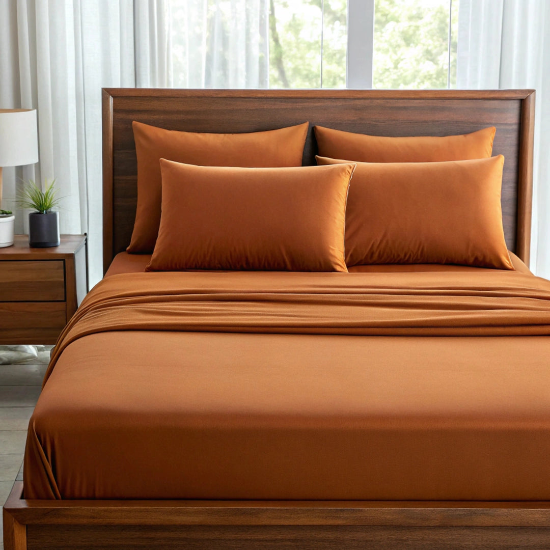Front-facing view of a queen bed with rust bamboo sheets and pillowcases, styled with a sateen finish and deep pocket fit.