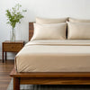 Side angle shot from pillow-end showing summer sand bamboo pillowcases and sheet set with decorative plant and soft lighting.