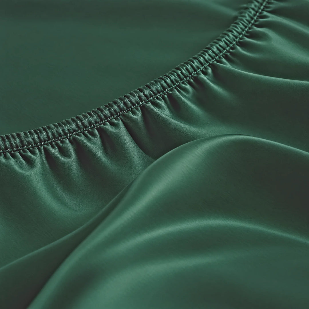 Emerald Green bamboo viscose Signature fitted sheet macro close-up of smooth silky sateen folds and a stitched elastic hem