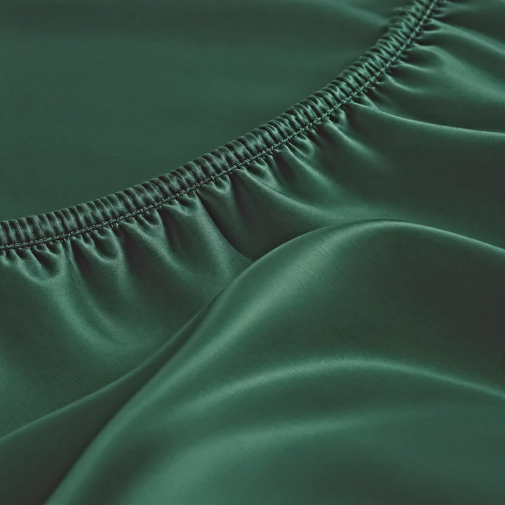 Emerald Green bamboo viscose Signature fitted sheet macro close-up of smooth silky sateen folds and a stitched elastic hem