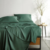 emerald green bamboo bed sheets with sateen weave from the Signature Collection, shown from the foot of the bed with a draped flat sheet and matching pillowcases