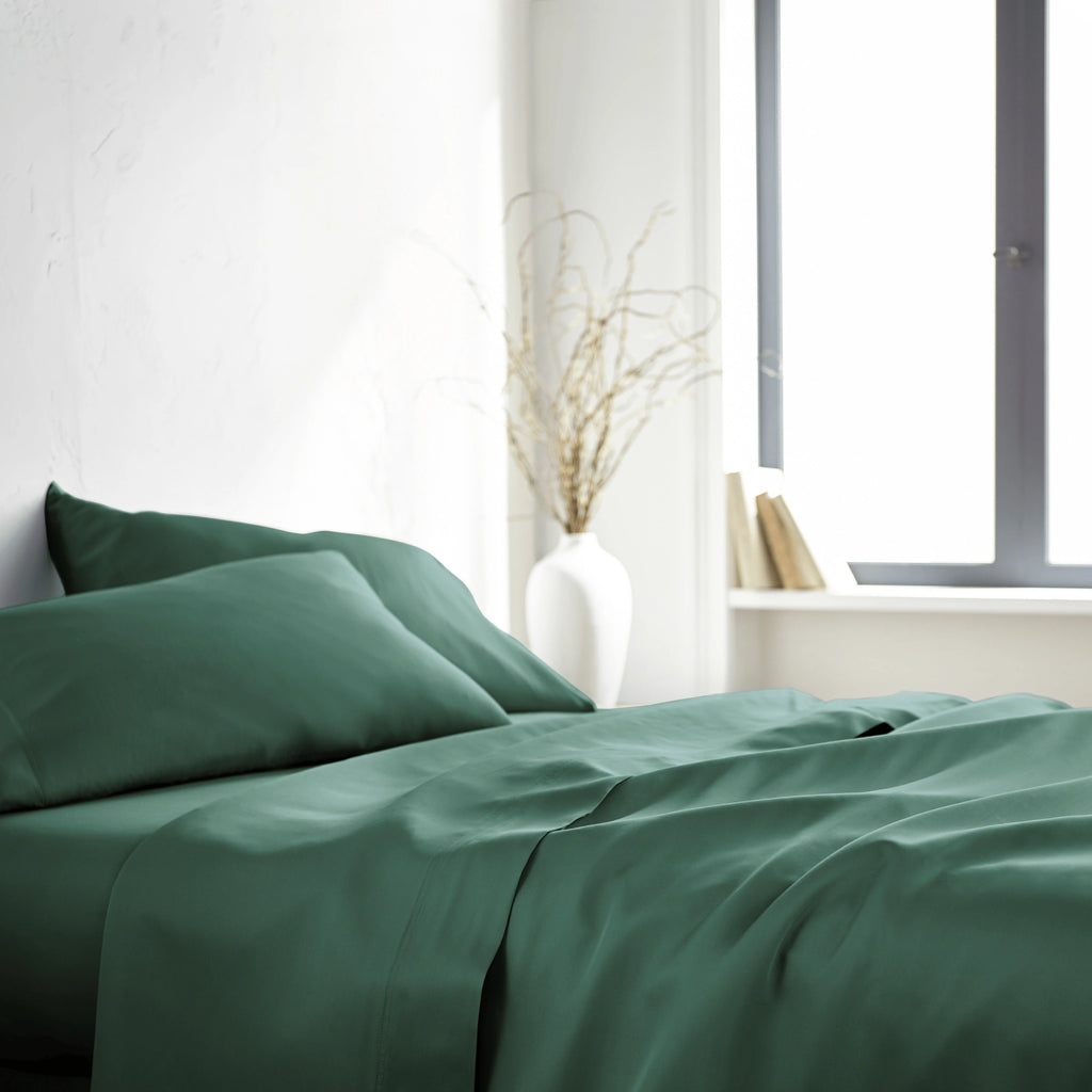 emerald green bamboo bed sheets with sateen weave from the Signature Collection, side angle view with window lighting and soft fabric drape