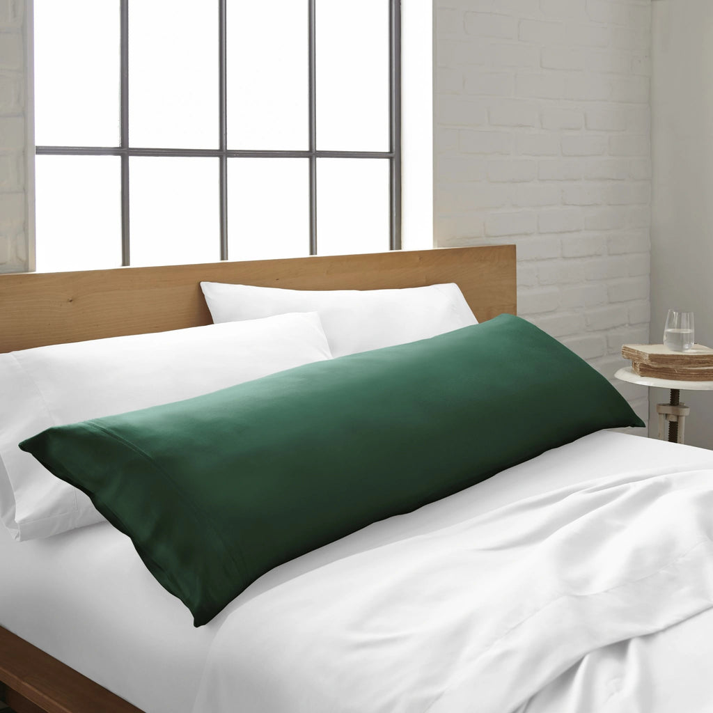 emerald green bamboo body pillow from the Signature Collection, shown on a emerald green bed in a bright modern bedroom with natural light and wood headboard