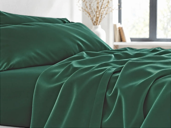 Emerald Green bamboo viscose flat sheet close-up billowing over the mattress edge in relaxed sateen folds