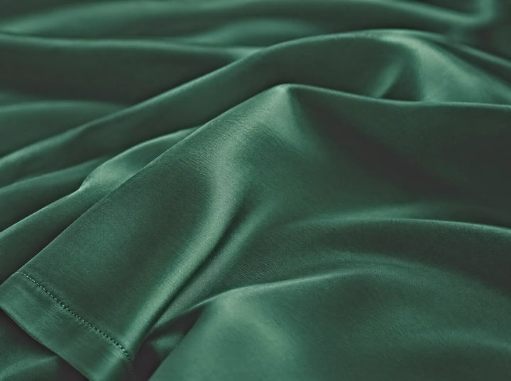 Emerald Green bamboo viscose flat sheet macro close-up of smooth silky sateen folds and a stitched hem