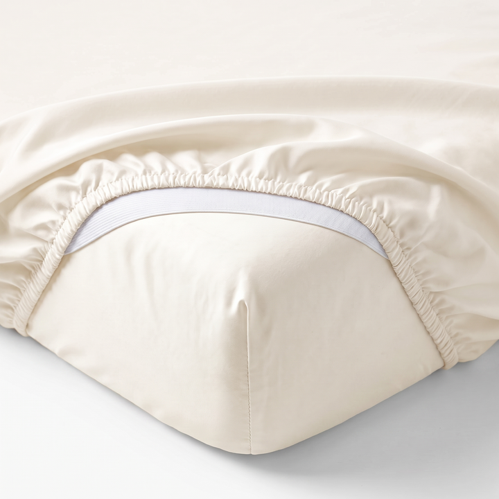 ivory bamboo sateen fitted sheet corner with white elastic strap, showing snug fit and smooth fabric texture