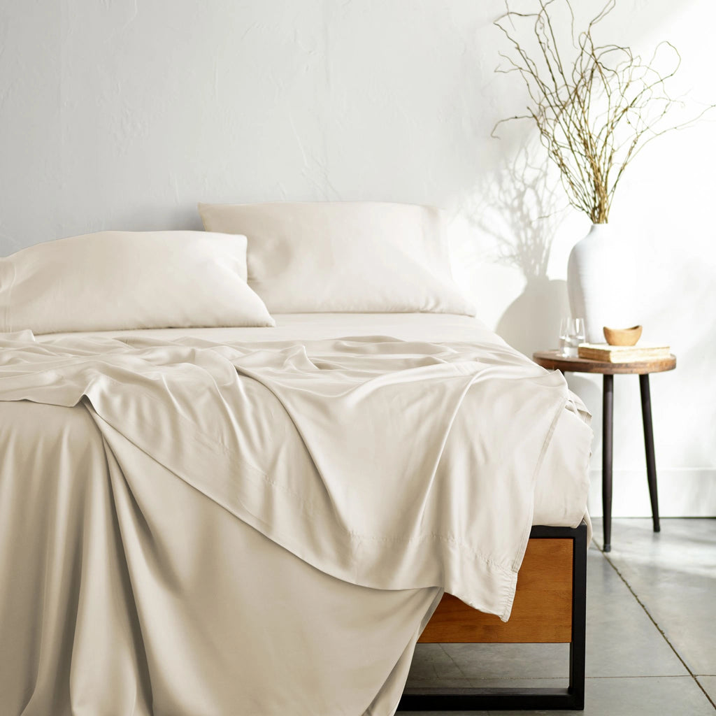 ivory bamboo bed sheets with sateen weave from the Signature Collection, shown from the foot of the bed with a draped flat sheet and matching pillowcases