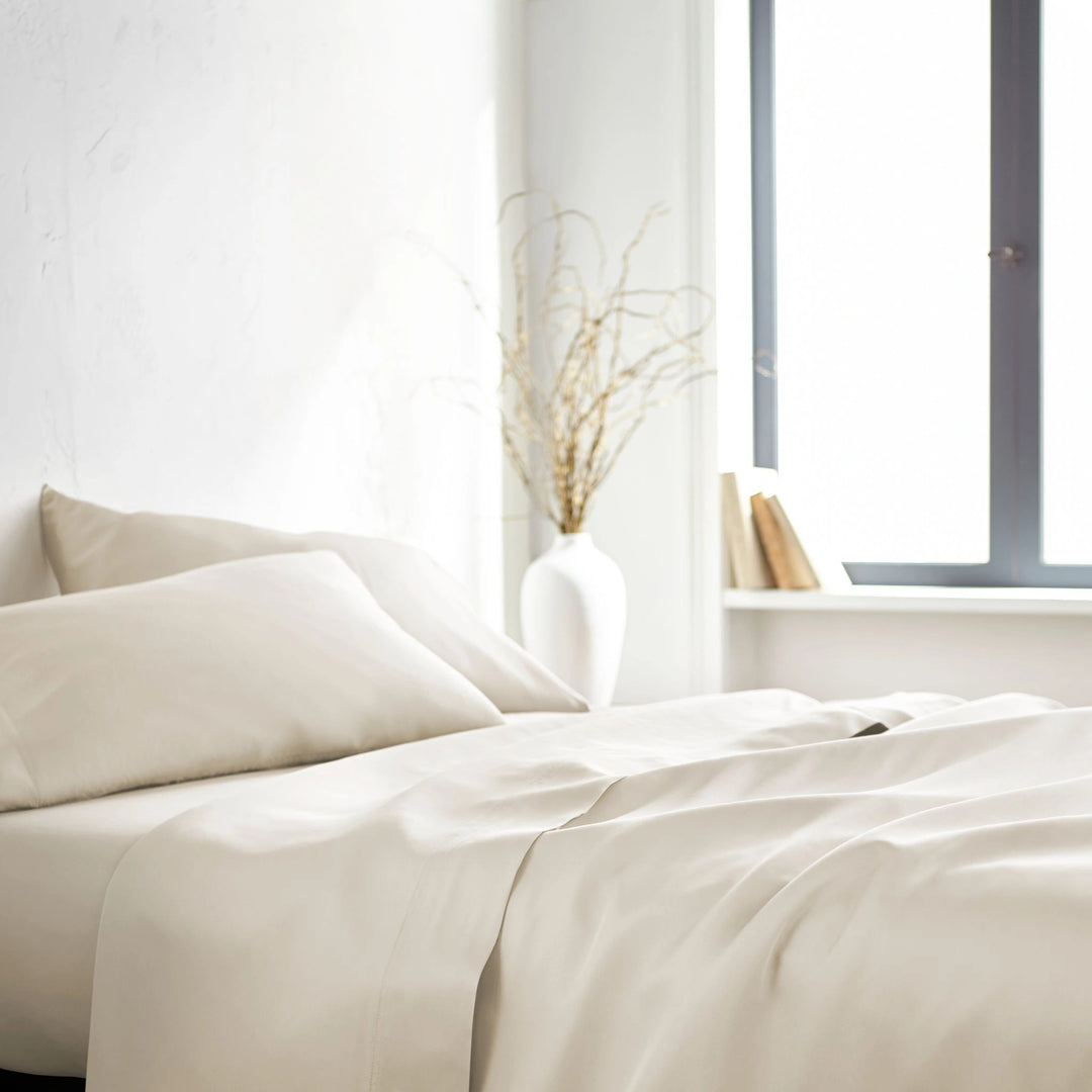 ivory bamboo bed sheets with sateen weave from the Signature Collection, side angle view with window lighting and soft fabric drape
