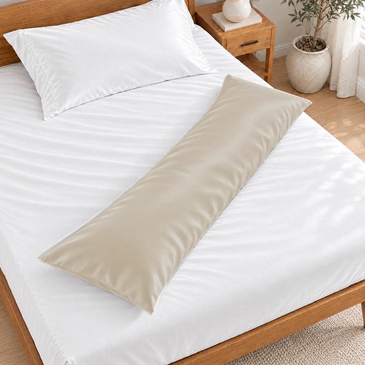 Ivory bamboo viscose sateen body pillowcase lying diagonally across a made bed, overhead view in a bright bedroom with a honey bamboo bed