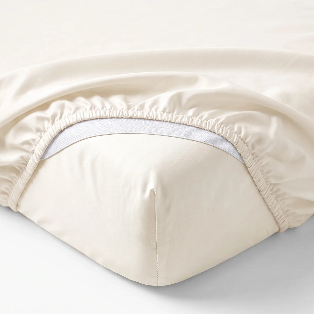 ivory bamboo sateen fitted sheet corner with white elastic strap, showing snug fit and smooth fabric texture