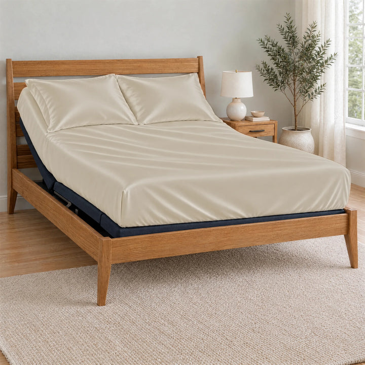 Ivory bamboo viscose Signature fitted sheet on a made bed with a bamboo frame and nightstand in a bright bedroom