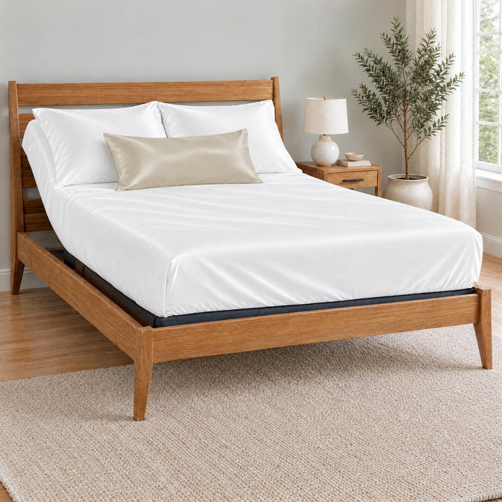 Ivory bamboo viscose sateen lumbar pillowcase on a made bed in front of white pillows in a light oak bedroom with an olive tree