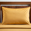Mustard yellow bamboo pillowcase styled on a walnut bed, featuring breathable, antibacterial fabric ideal for acne-prone or sensitive skin.