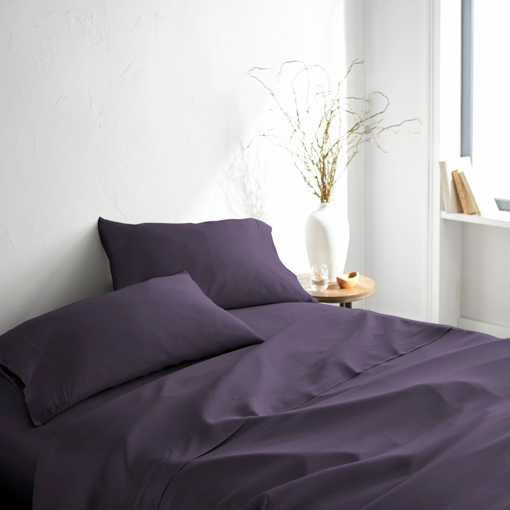 royal purple bamboo bed sheets with sateen weave from the Signature Collection, shown front view with matching pillowcases and a modern nightstand