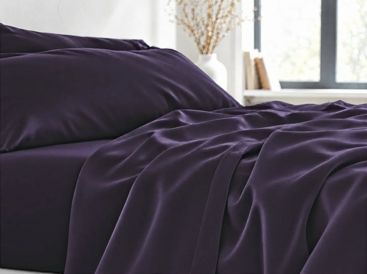 Royal Purple bamboo viscose flat sheet close-up billowing over the mattress edge in relaxed sateen folds